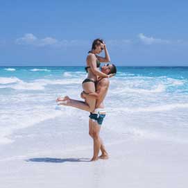 a man carrying a woman on a beach