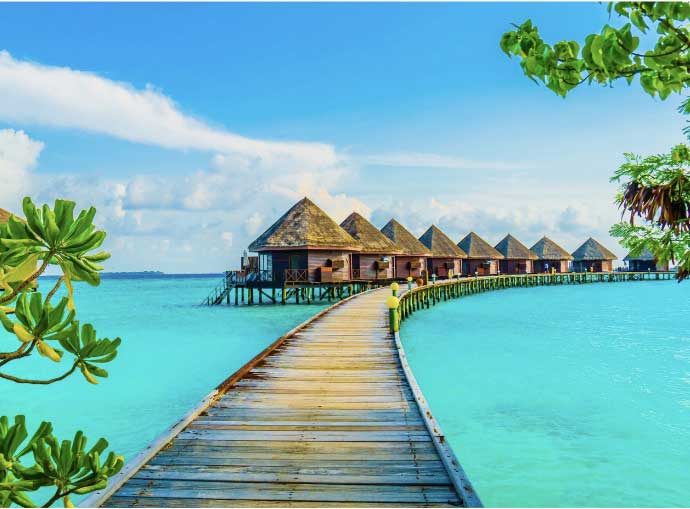 a wooden walkway leading to a row of huts on stilts