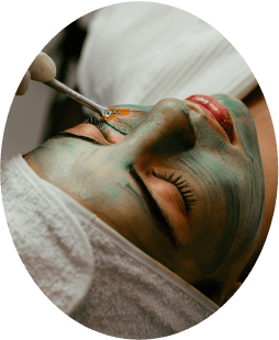 a person applying a green mask on a woman's face