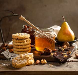 a jar of honey next to cookies and fruit