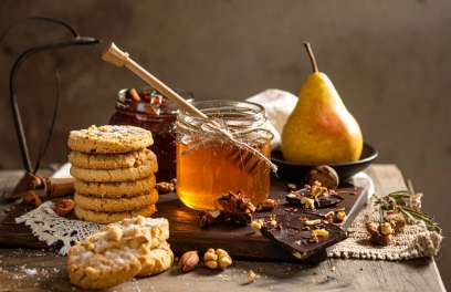 a jar of honey next to cookies and fruit