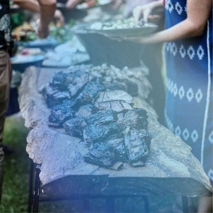 a group of people standing around a table full of food