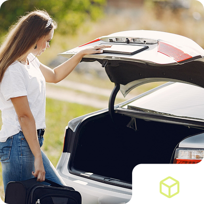 a woman holding a suitcase in the trunk of a car