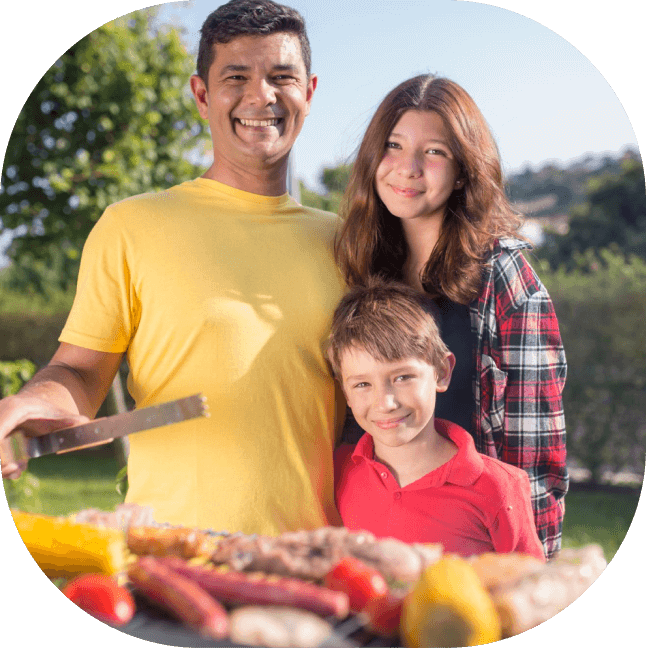 a man and woman standing next to a boy and a grill