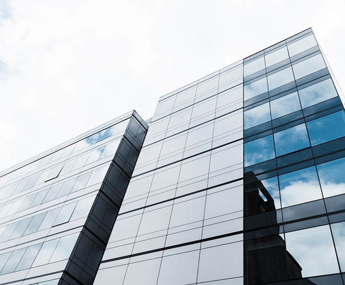 a glass building with a reflection of clouds in the windows