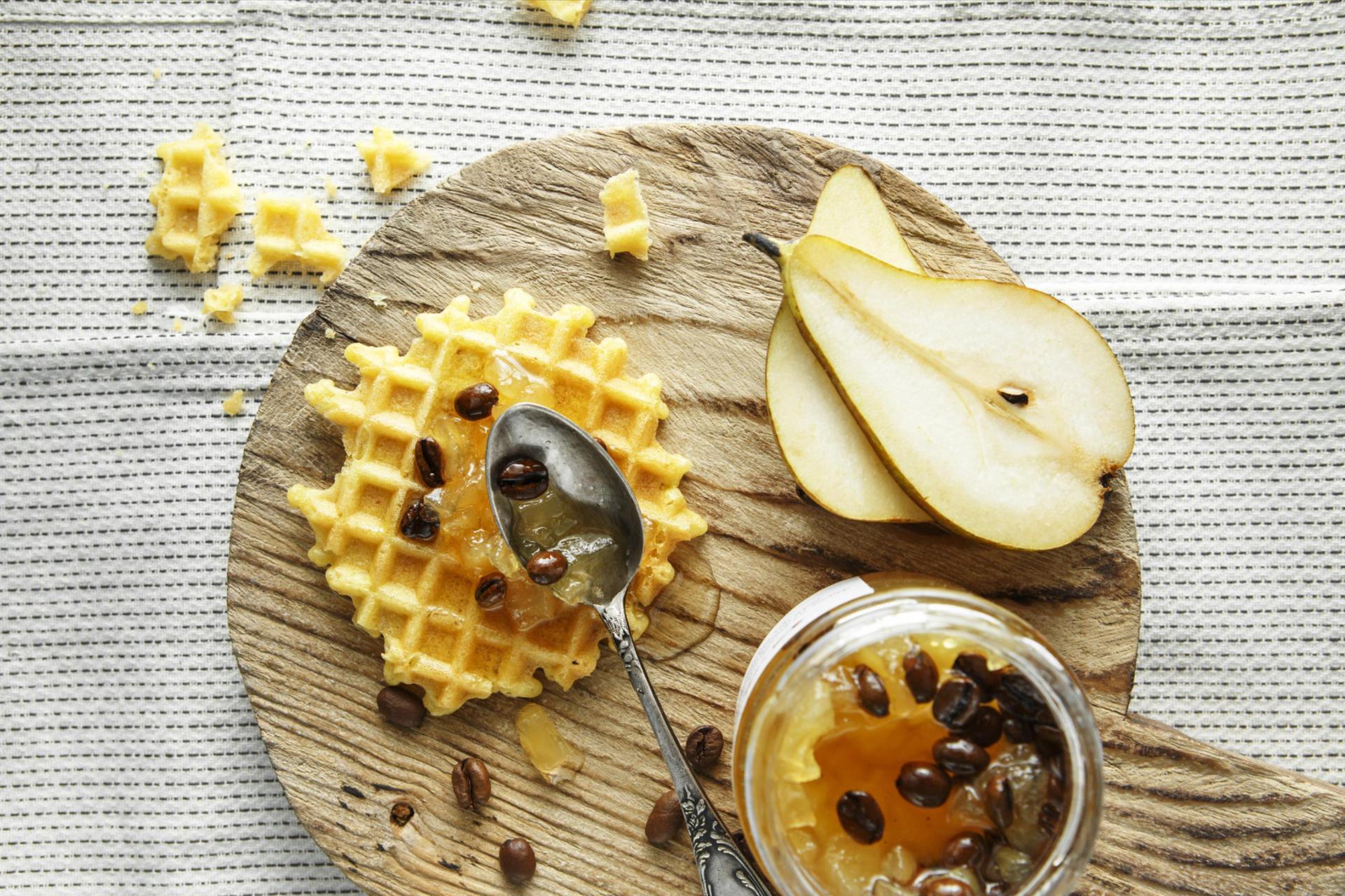 Top view of waffles and pear jam, coffee beans and slices of pears