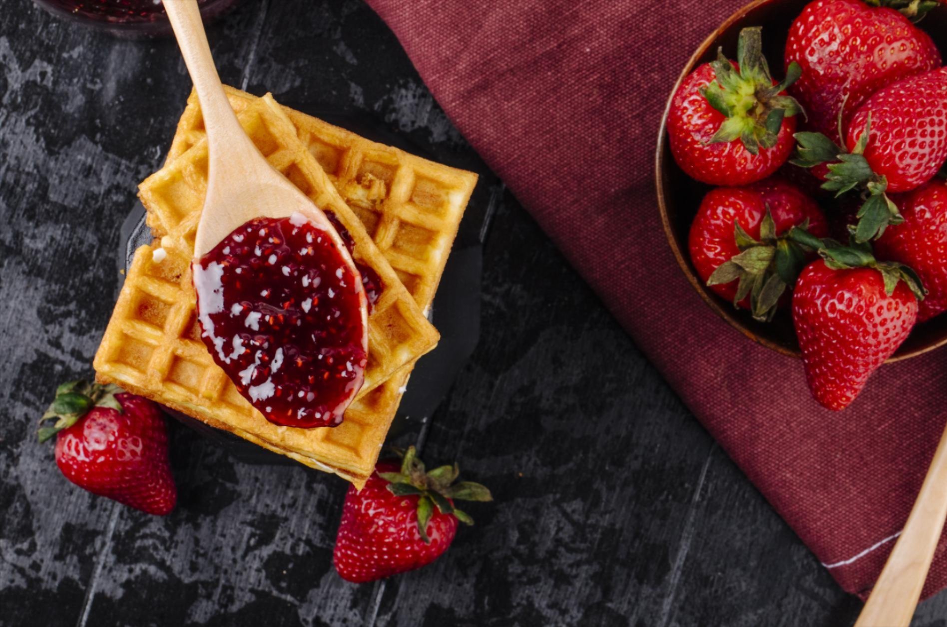 Top view of waffles and strawberry jam and a strawberry bowl