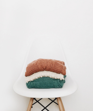 Pile of colorful sweaters on a white chair
