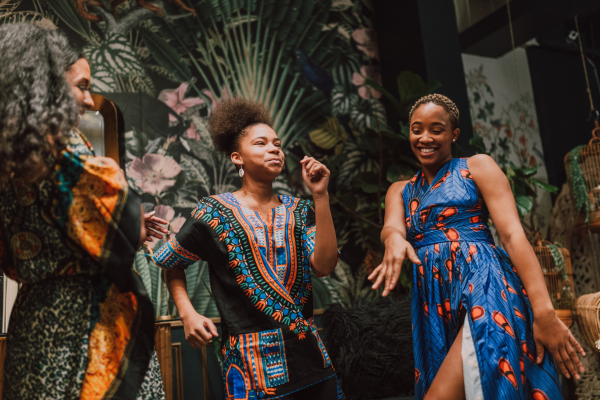 Group of black women wearing colorfull dresses happily dancing