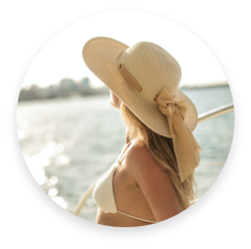 Blonde girl with beige straw hat staring at the sea