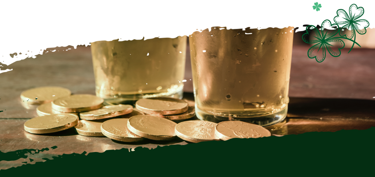 Two pints of beer on a table next to gold coins