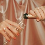 Female hands pouring champagne in a glass.