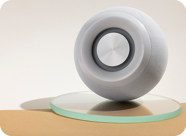 a round white speaker on a glass coaster