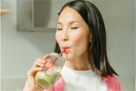 a woman drinking from a jar with a straw