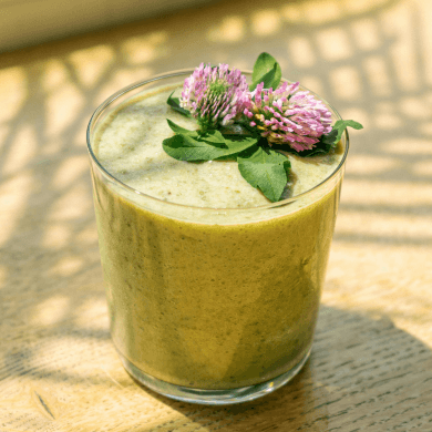 a glass of green smoothie with flowers on top