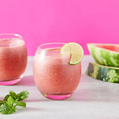 a two glasses of pink drink with a slice of lime and mint