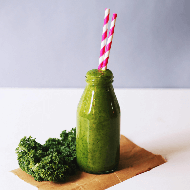 a green smoothie in a bottle with two straws