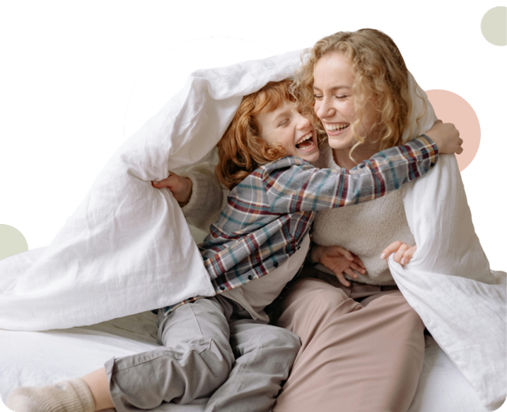 a woman and child laughing under a blanket