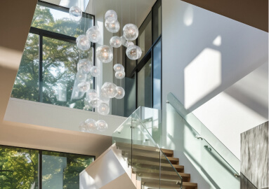 a staircase with glass railings and chandelier