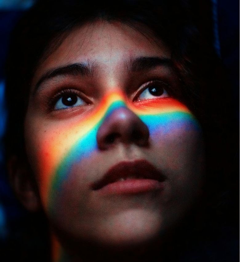 a woman looking up with rainbow on her face