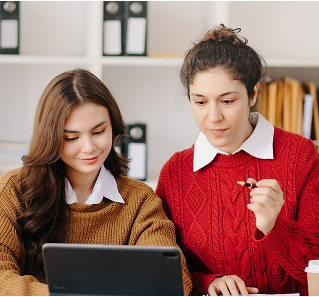 a couple of women looking at a laptop