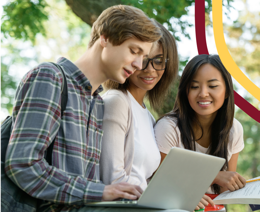 a group of people sitting outside looking at a laptop