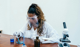 a woman wearing a white coat and face shield