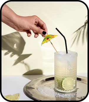 a hand holding a glass of yellow liquid