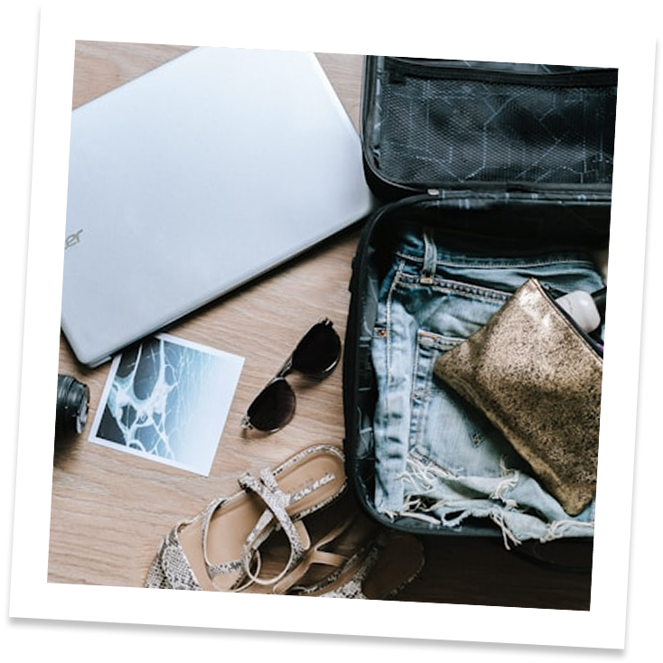 a suitcase with jeans and shoes and a laptop