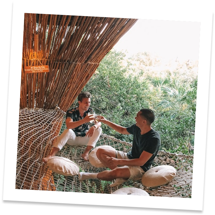 two men sitting on a hammock
