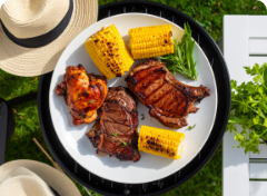 a plate of grilled meats and corn on a table
