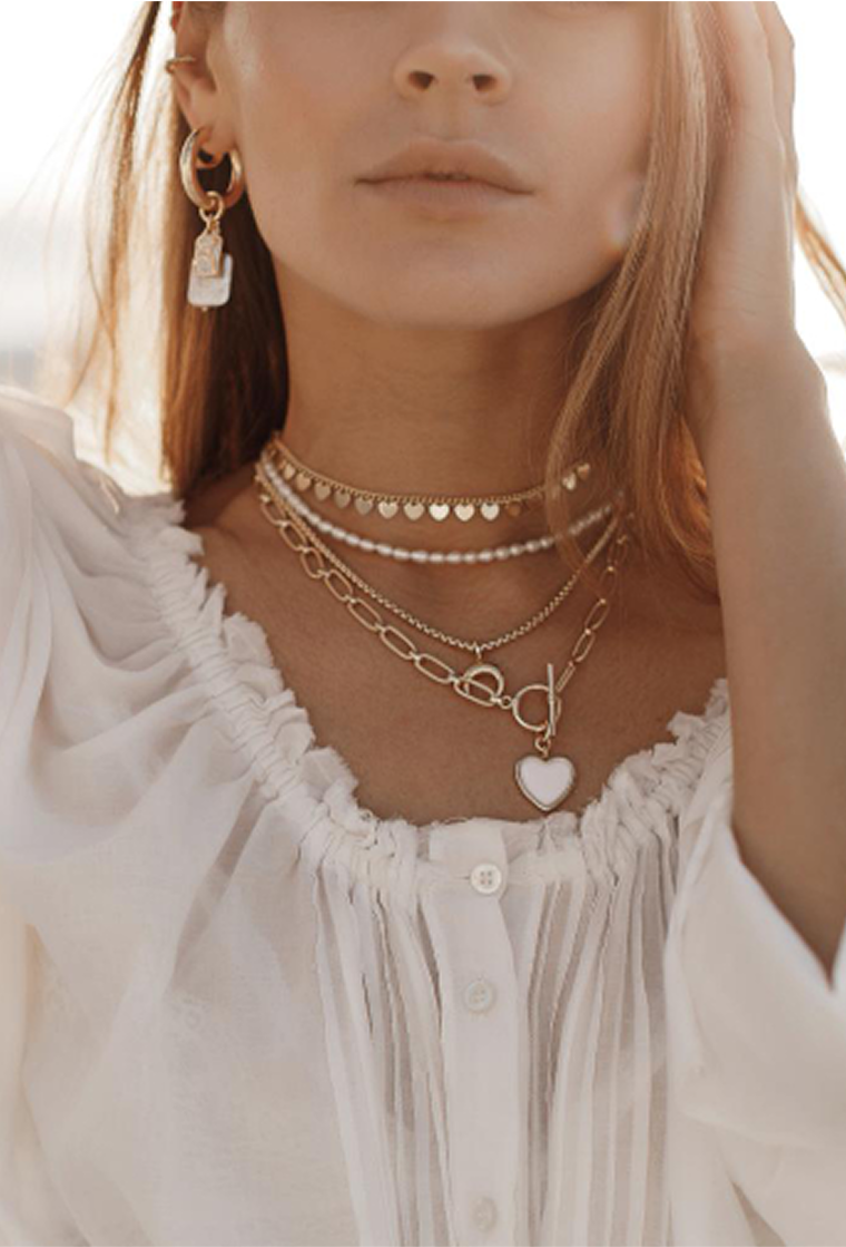 a woman wearing a white blouse and gold necklace