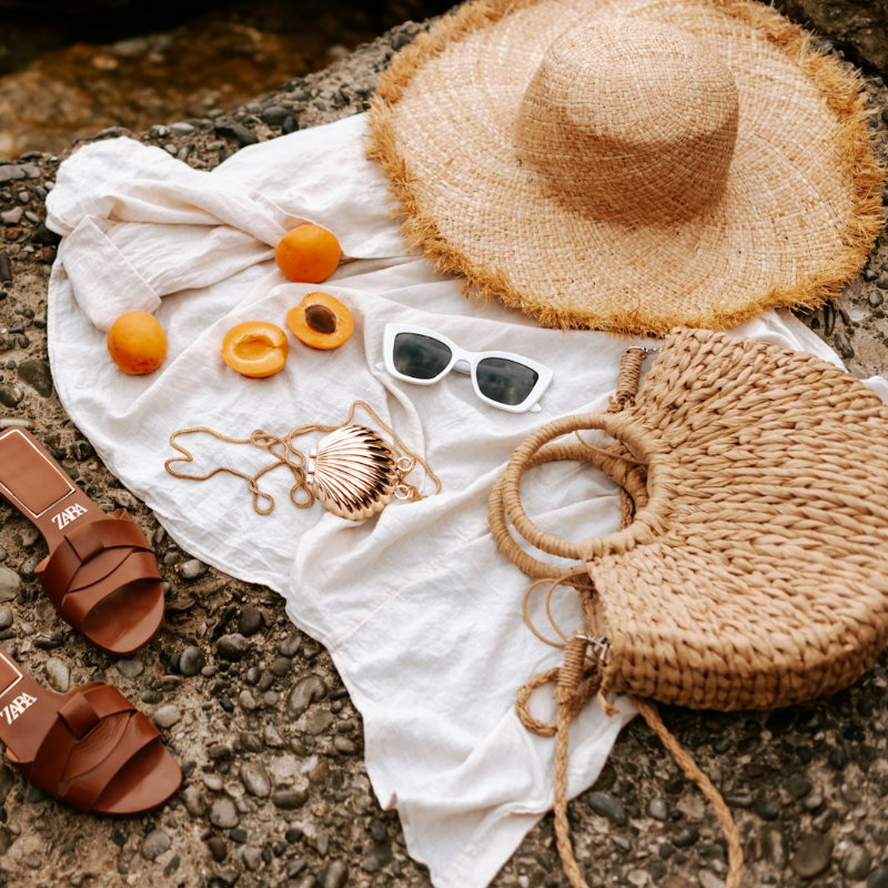 a straw hat and sunglasses on a rock